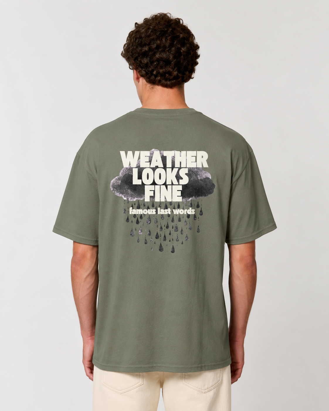 Person wearing a green t-shirt with 'Weather Looks Fine' text on the back against a plain background